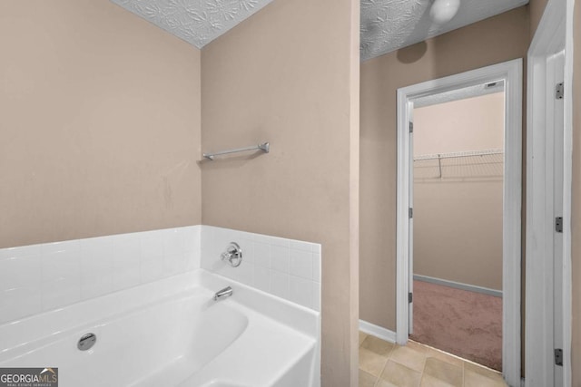 bathroom with a bathing tub, tile patterned floors, and a textured ceiling