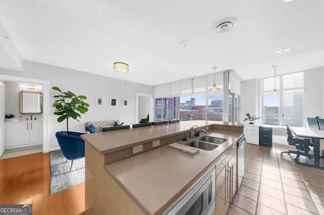 kitchen with white cabinetry, a kitchen island with sink, a breakfast bar area, and decorative light fixtures