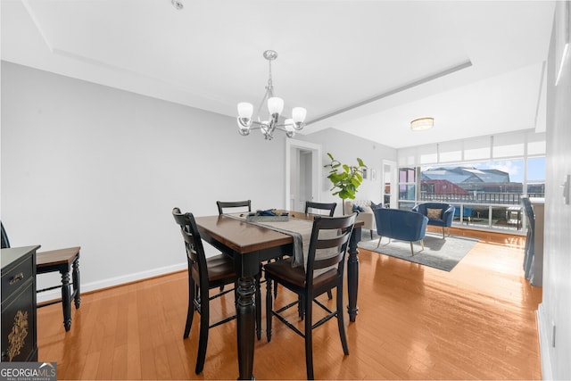 dining room featuring a wall of windows, light hardwood / wood-style floors, and a chandelier