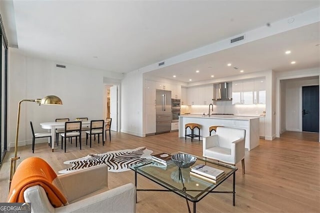 living room featuring sink and light hardwood / wood-style flooring