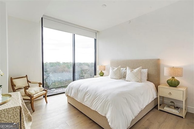 bedroom with expansive windows and light wood-type flooring