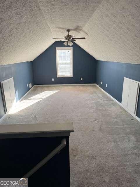 additional living space with lofted ceiling, ceiling fan, a textured ceiling, and carpet