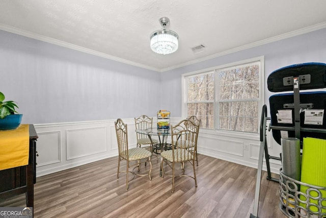 dining area with ornamental molding, hardwood / wood-style floors, and an inviting chandelier