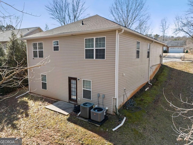 rear view of property with a garage and central air condition unit