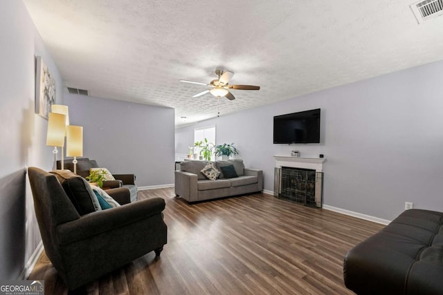 living room with ceiling fan, a textured ceiling, and dark hardwood / wood-style flooring