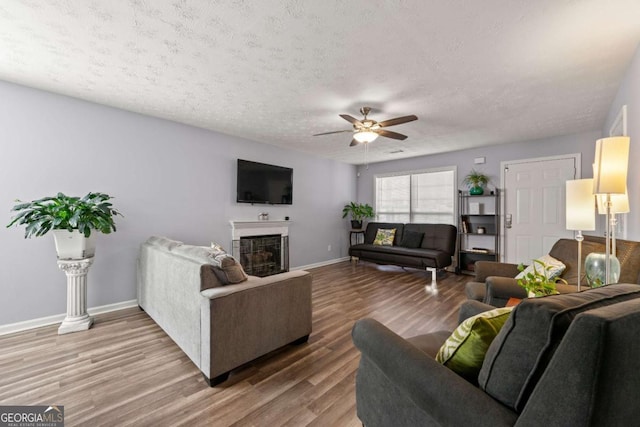 living room featuring ceiling fan, hardwood / wood-style flooring, and a textured ceiling