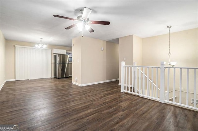 unfurnished living room featuring dark hardwood / wood-style floors and ceiling fan with notable chandelier