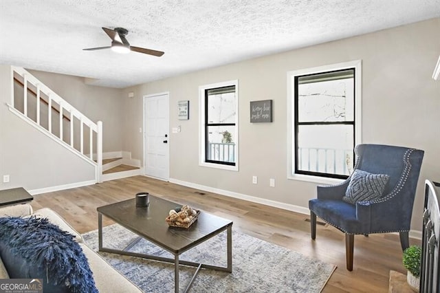 living room with wood-type flooring, ceiling fan, and a textured ceiling