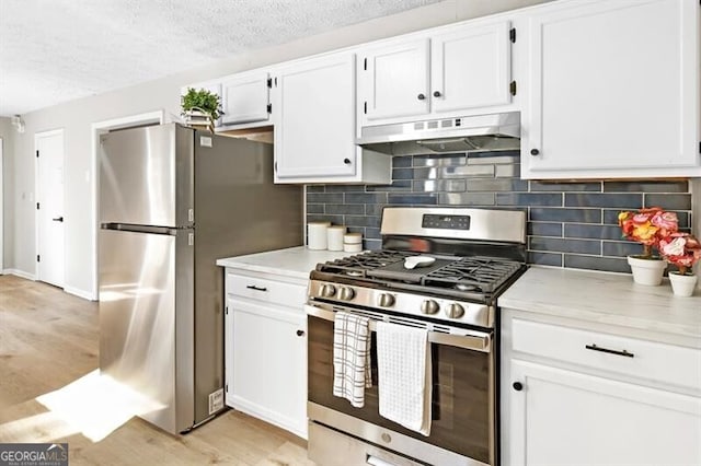 kitchen featuring stainless steel appliances, tasteful backsplash, light hardwood / wood-style floors, a textured ceiling, and white cabinets