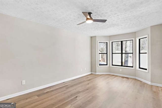 unfurnished room with ceiling fan, a textured ceiling, and light wood-type flooring