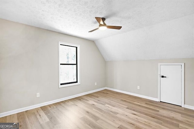 bonus room featuring ceiling fan, lofted ceiling, light hardwood / wood-style floors, and a textured ceiling