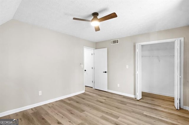 unfurnished bedroom featuring ceiling fan, light hardwood / wood-style flooring, a closet, and a textured ceiling