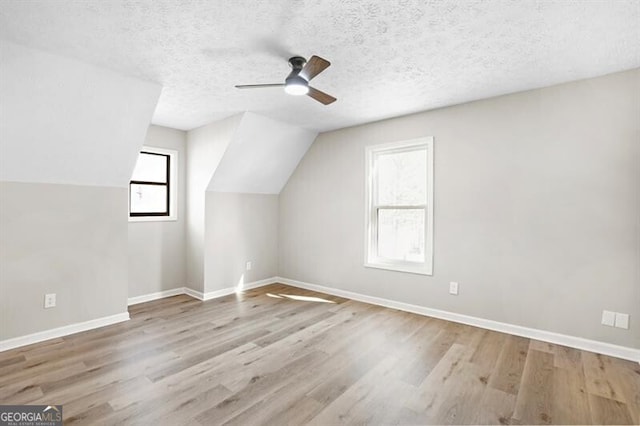 additional living space with lofted ceiling, ceiling fan, light hardwood / wood-style flooring, and a textured ceiling