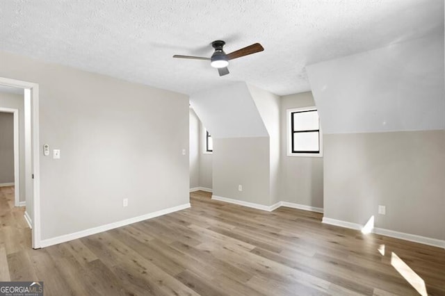 additional living space with ceiling fan, lofted ceiling, hardwood / wood-style floors, and a textured ceiling