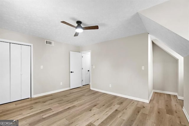 bonus room featuring ceiling fan, lofted ceiling, a textured ceiling, and light hardwood / wood-style floors