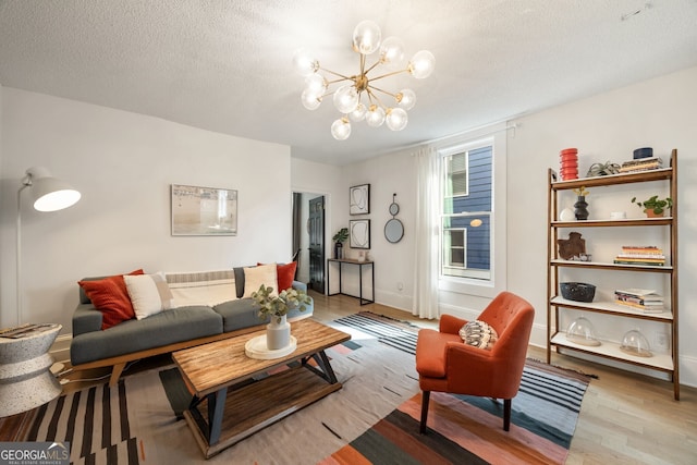 living room with a chandelier, light hardwood / wood-style flooring, and a textured ceiling