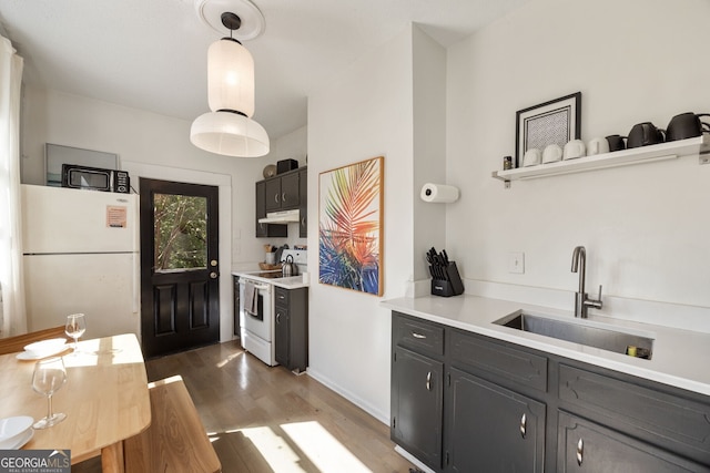 kitchen with hanging light fixtures, hardwood / wood-style flooring, sink, and white appliances