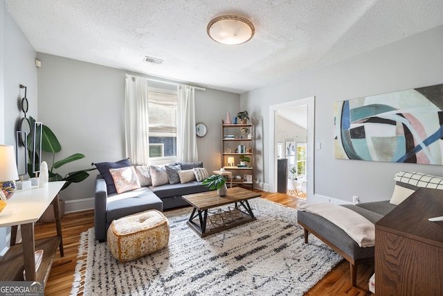 living room featuring wood-type flooring and a textured ceiling