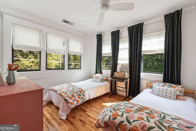 bedroom featuring multiple windows, ceiling fan, and light wood-type flooring