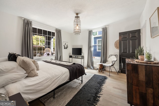 bedroom with multiple windows, light hardwood / wood-style flooring, and a textured ceiling