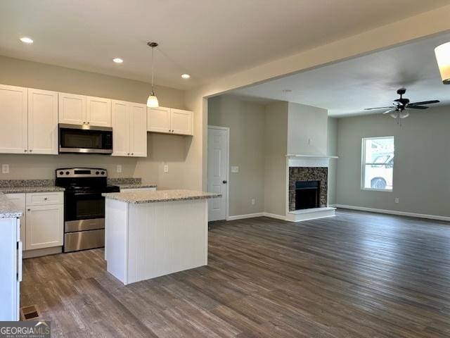 kitchen with light stone counters, decorative light fixtures, white cabinets, and appliances with stainless steel finishes