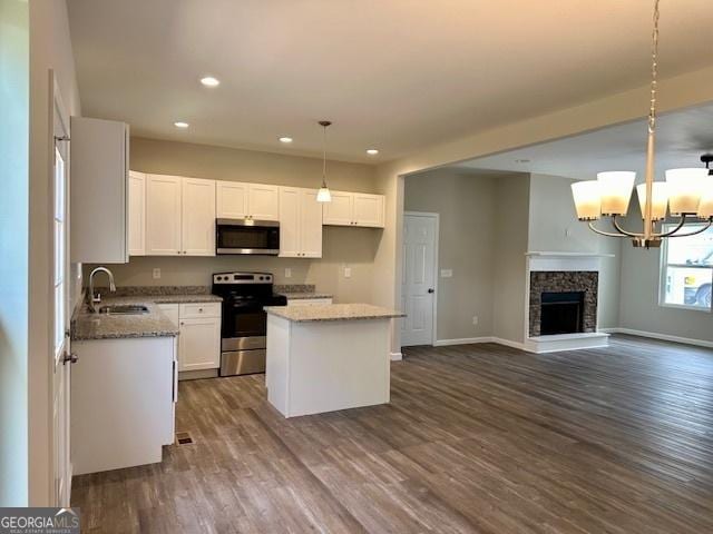 kitchen with sink, appliances with stainless steel finishes, white cabinetry, hanging light fixtures, and a kitchen island