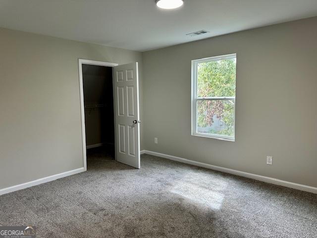 unfurnished bedroom featuring a closet, carpet flooring, and a spacious closet