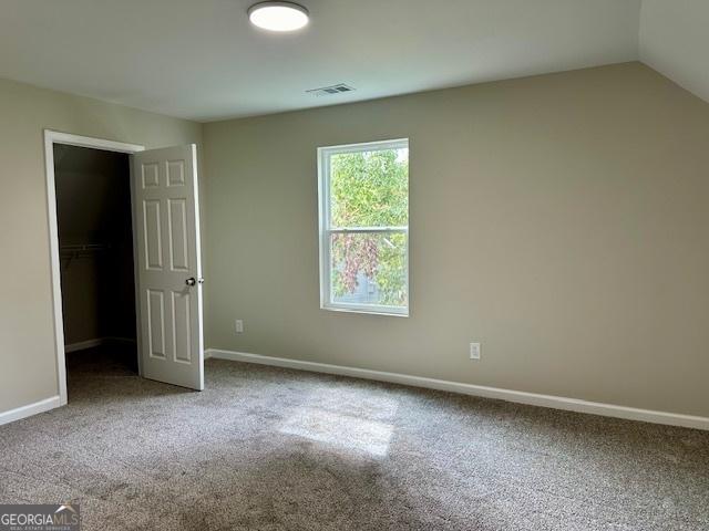 carpeted spare room with vaulted ceiling