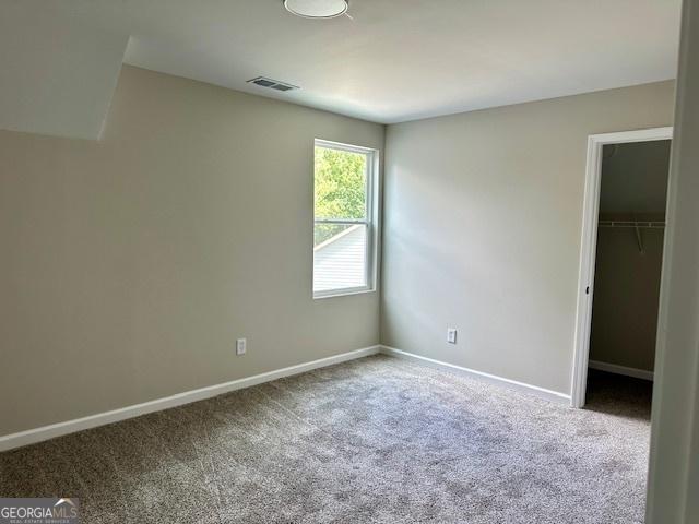 unfurnished bedroom featuring a spacious closet, carpet floors, and a closet