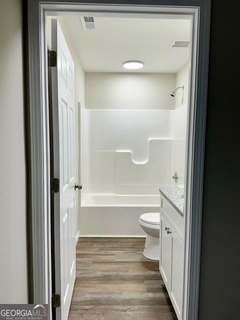 full bathroom featuring vanity, toilet,  shower combination, and wood-type flooring