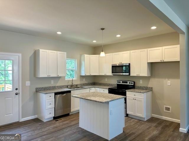 kitchen featuring sink, white cabinetry, stainless steel appliances, a center island, and decorative light fixtures