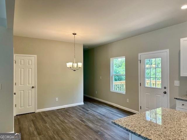 unfurnished dining area featuring a notable chandelier and dark wood-type flooring