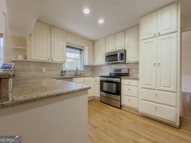 kitchen featuring light hardwood / wood-style flooring, stainless steel appliances, tasteful backsplash, light stone countertops, and white cabinets