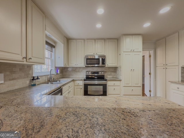 kitchen with stainless steel appliances, light stone countertops, sink, and decorative backsplash