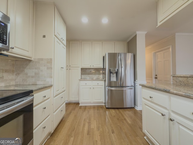 kitchen with light stone counters, light hardwood / wood-style floors, white cabinets, and appliances with stainless steel finishes