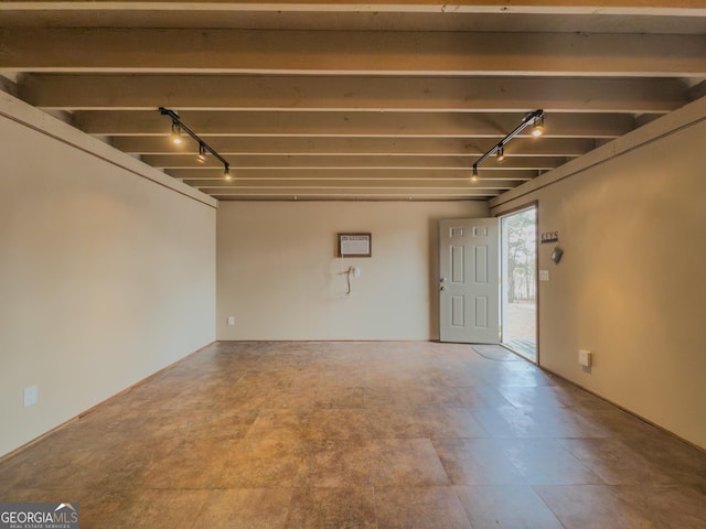 spare room with beam ceiling, track lighting, and an AC wall unit