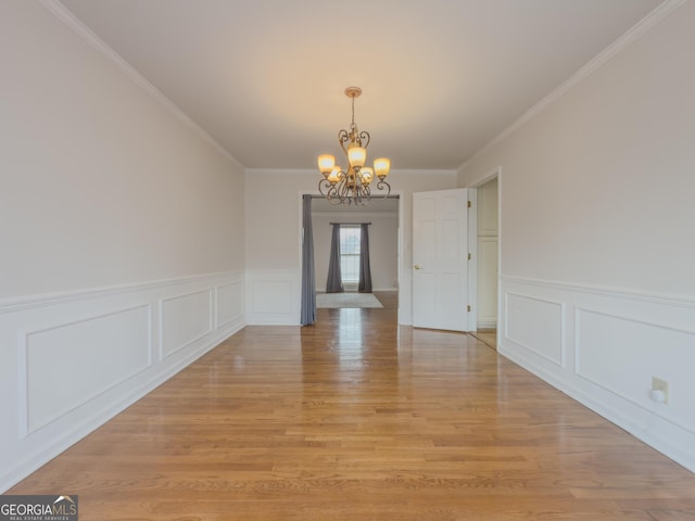 unfurnished dining area featuring an inviting chandelier, crown molding, and light hardwood / wood-style flooring