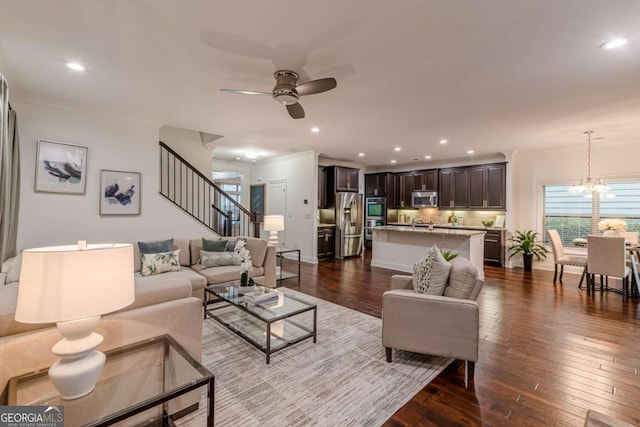 living room with ceiling fan with notable chandelier, ornamental molding, and dark hardwood / wood-style floors