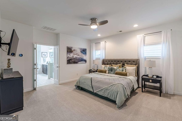 bedroom featuring ceiling fan, light colored carpet, and ensuite bath