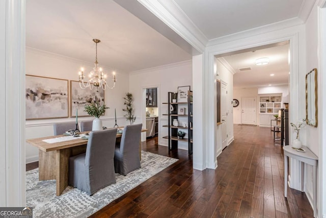 dining room with crown molding, dark wood-type flooring, and a notable chandelier