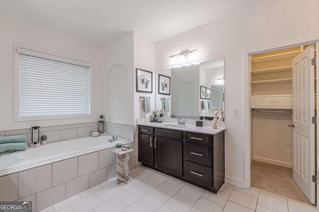 bathroom with vanity, a relaxing tiled tub, and tile patterned floors