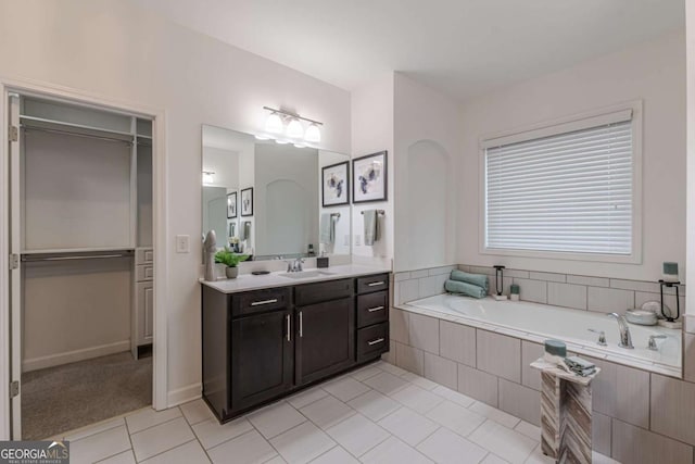 bathroom with tile patterned floors, vanity, and tiled bath