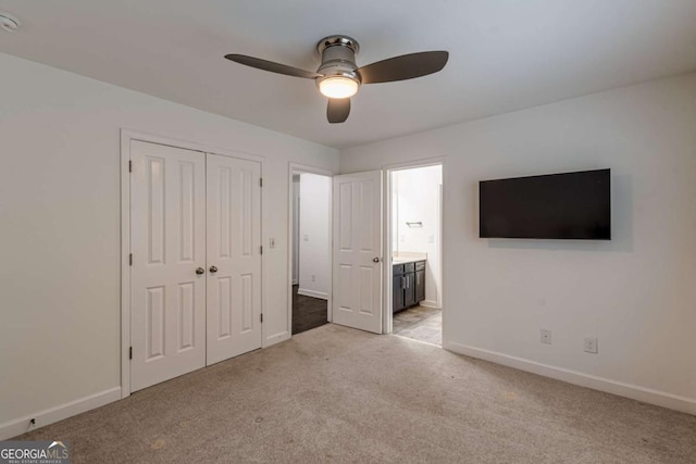 unfurnished bedroom featuring ceiling fan, light colored carpet, ensuite bath, and a closet