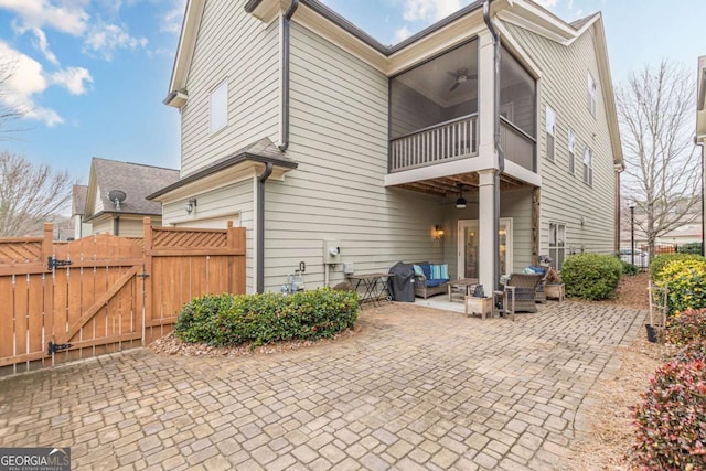 rear view of property with ceiling fan and a patio