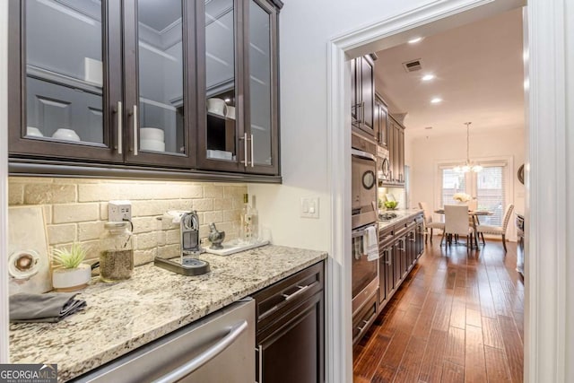 kitchen featuring dark wood-type flooring, appliances with stainless steel finishes, dark brown cabinets, tasteful backsplash, and decorative light fixtures