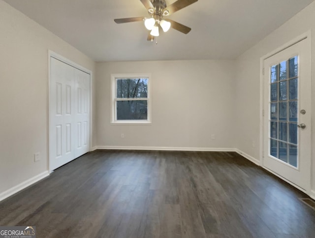 empty room featuring plenty of natural light, dark hardwood / wood-style floors, and ceiling fan