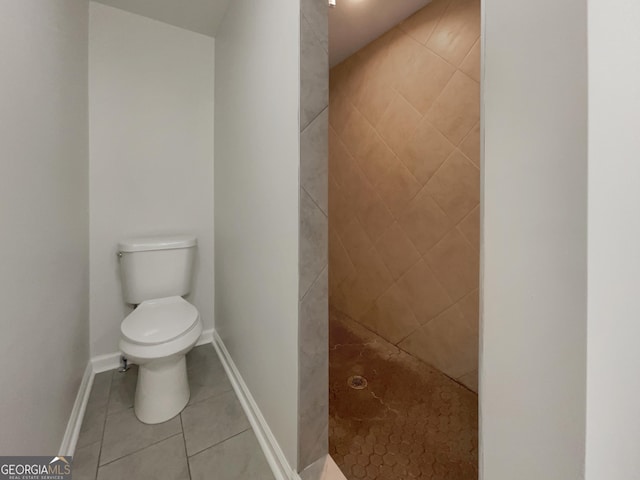 bathroom with tile patterned floors, toilet, and tiled shower