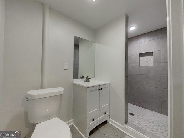 bathroom with vanity, a tile shower, tile patterned floors, and toilet