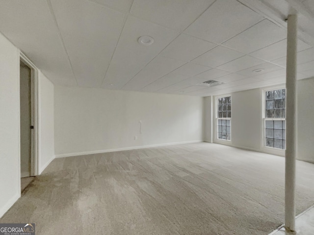 spare room with a paneled ceiling and light colored carpet