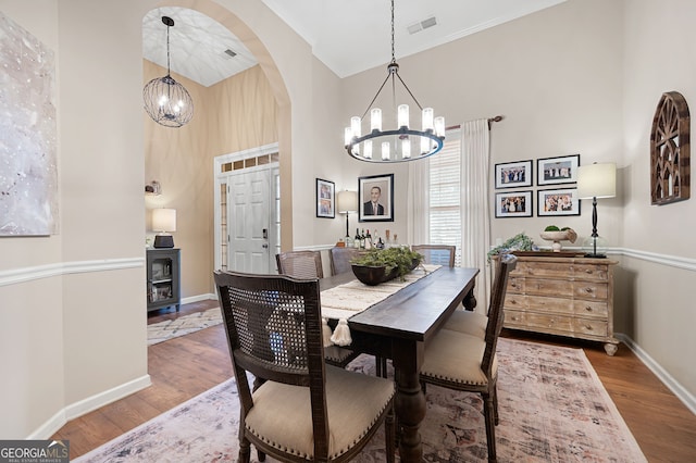 dining room with hardwood / wood-style floors, a chandelier, and a high ceiling